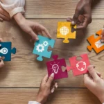 Hands holding different parts of puzzle pieces that all fit together.