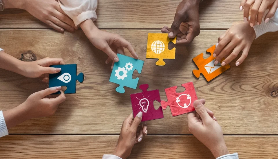 Hands holding different parts of puzzle pieces that all fit together.