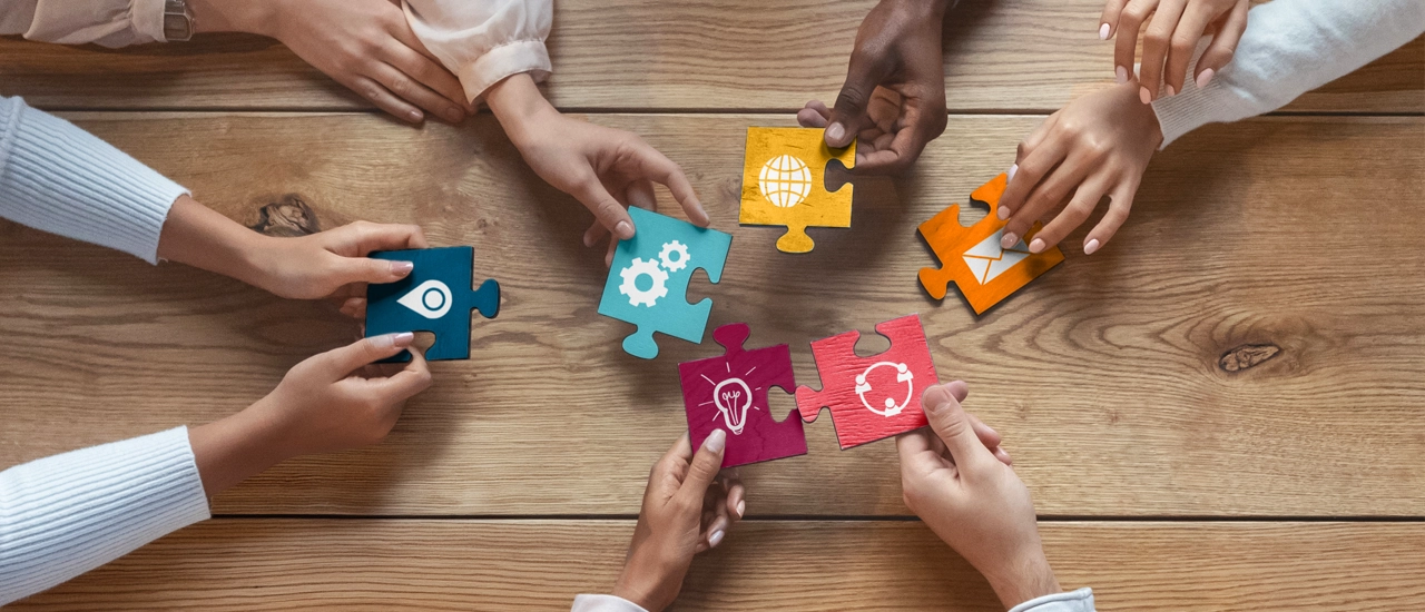 Hands holding different parts of puzzle pieces that all fit together.